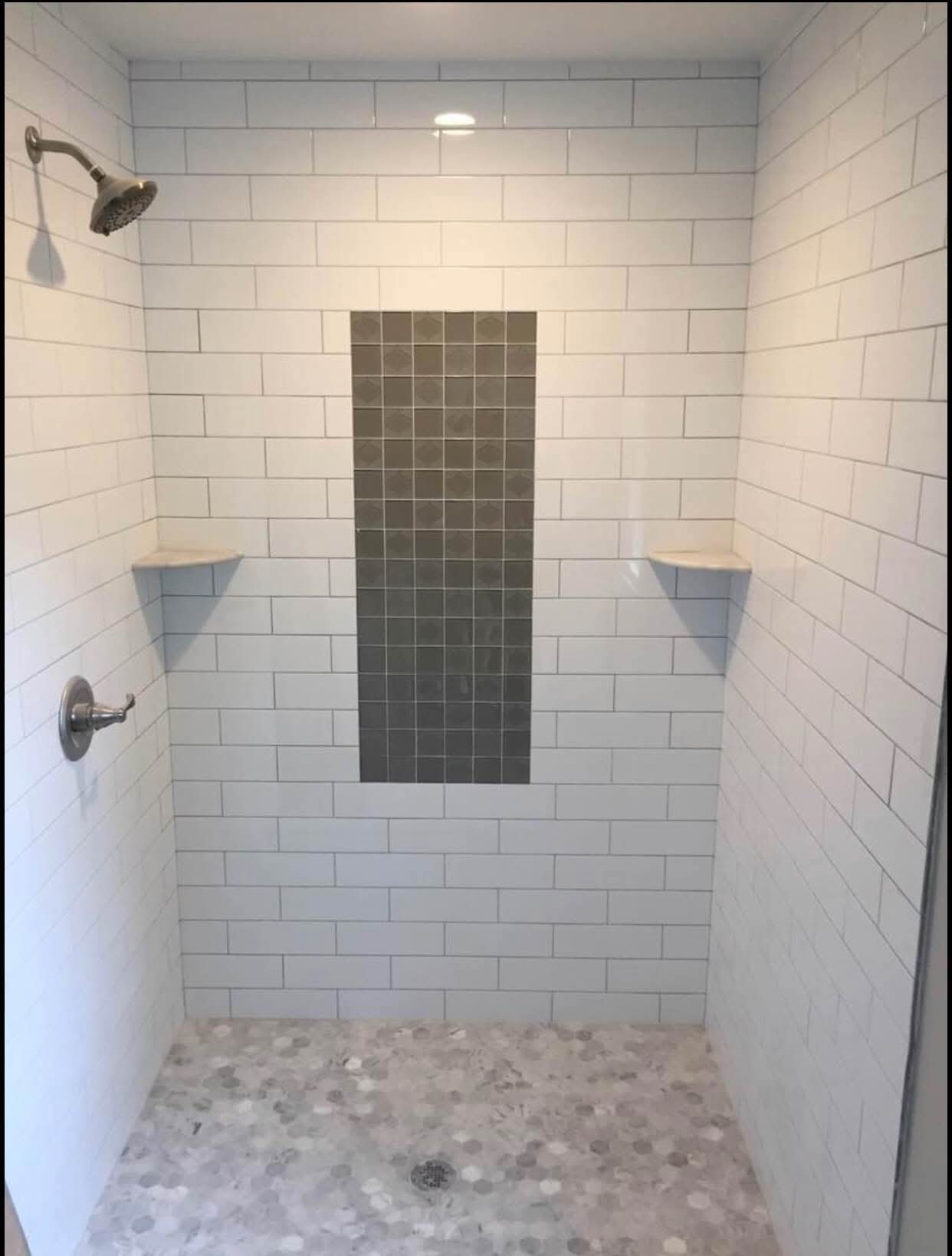 Duche com revestimento branco e nicho central em tons escuros